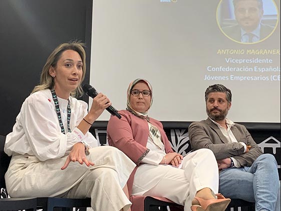 Imagen de tres partipantes en el escenario de los partipantes hablando en el evento El poder Creativo de los migrantes